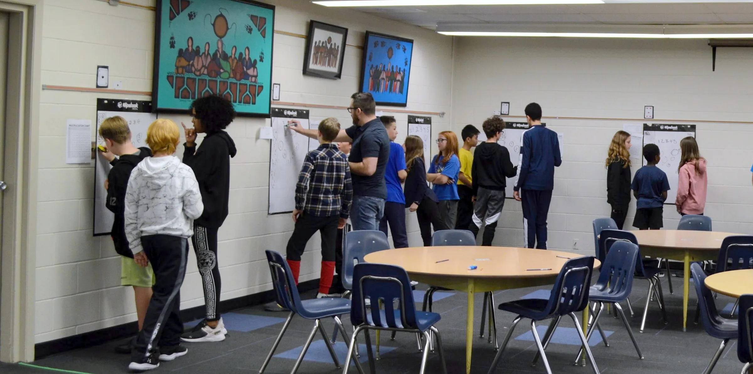 Students working in groups at whiteboards around a classroom
