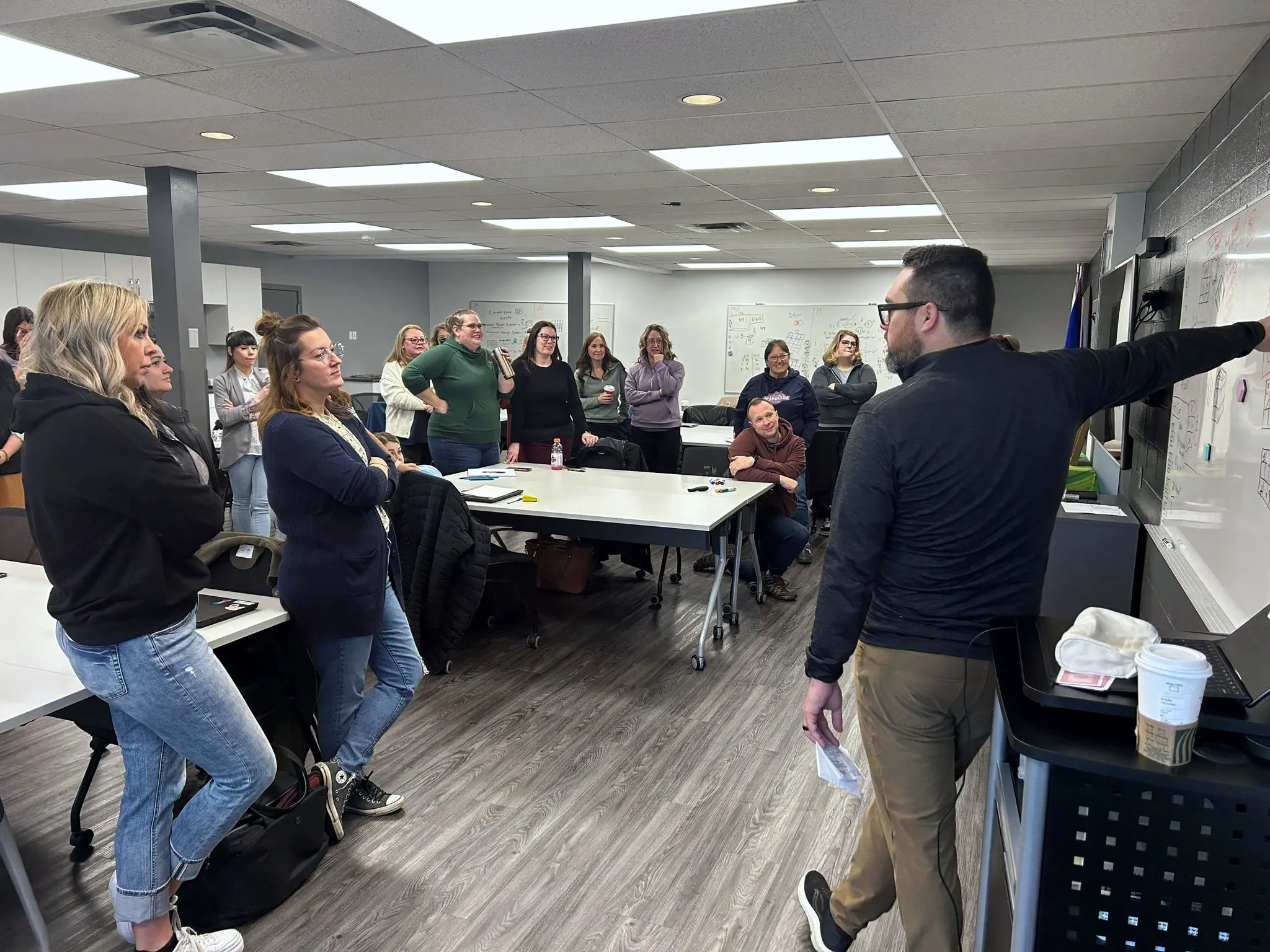 Kyle pointing to a whiteboard as teachers stand around the room during a workshop